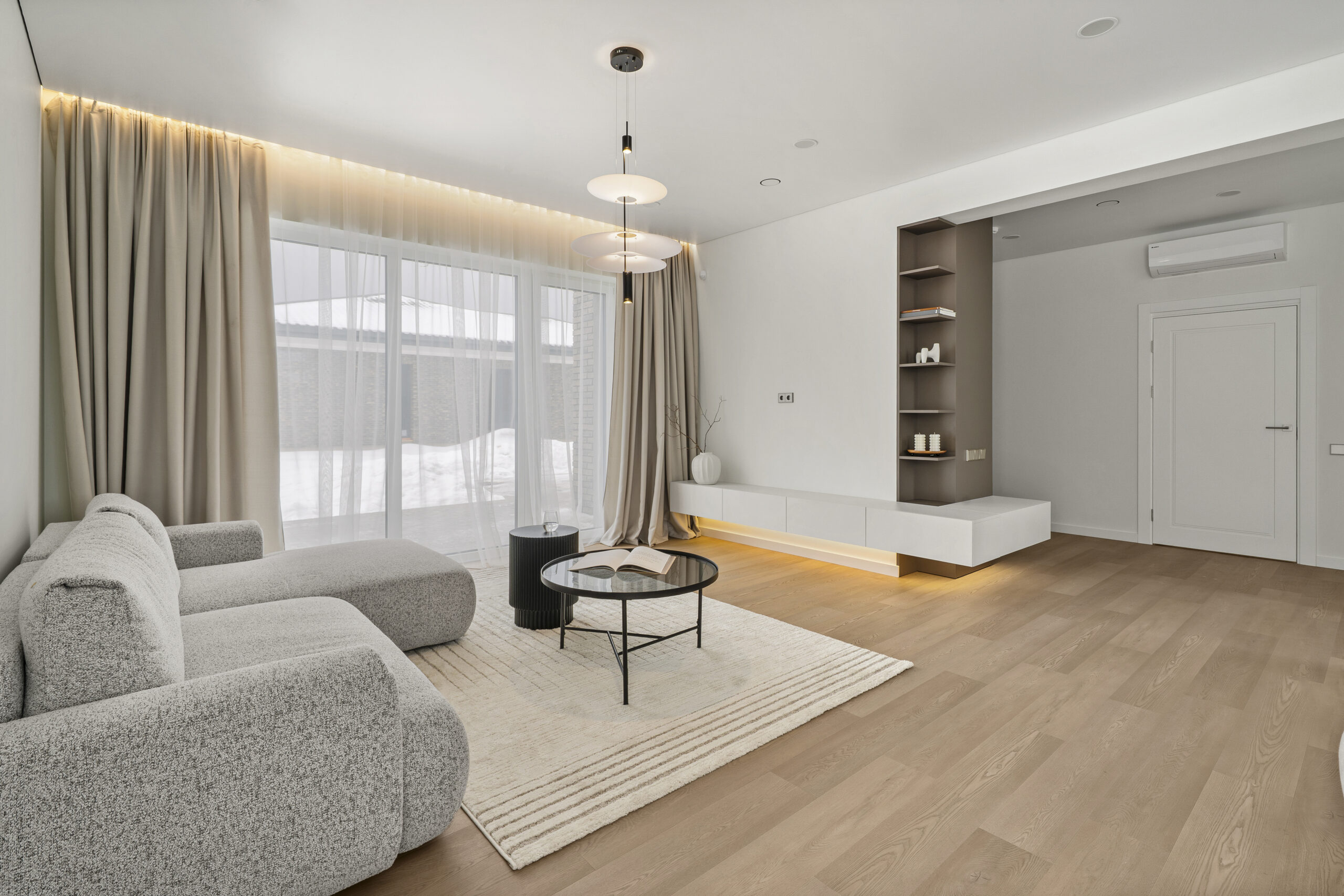Moderni japandi svetainė, šviesūs elementai su kakaviniais akcentais, pilka sofa